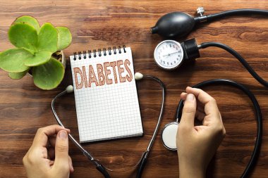 hastalık beyaz defter ve siyah stetoskop, ahşap masa üzerinde el kadın ile sphygmomanometer üzerine yazma diyabet kavramı metin durdurmak