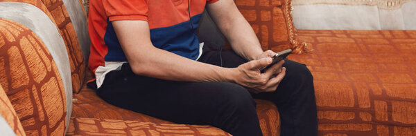 Человек, сидящий на марокканском диване и использующий смартфон
