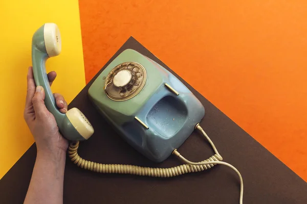 old retro phone isolated on colorful background and hand holding handset
