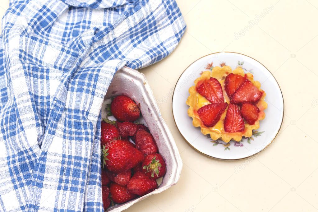 carton box of freshly picked strawberries  and blue napkin and tart 
