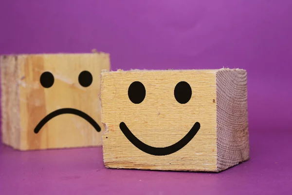 smiley face and blurred sad face icon on big wood cube, Service rating, satisfaction concept