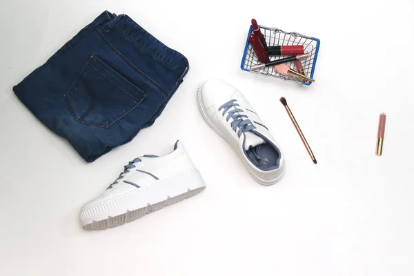 女性コレクション 白い背景に隔離されたカートの買い物に化粧をした青いジーンズと白のスニーカー — ストック写真