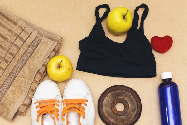 Sports equipment flat lay, and sneakers, old metal dumbbells and apples, water bottle and heart pillow. Concept healthy lifestyle, sport and diet.