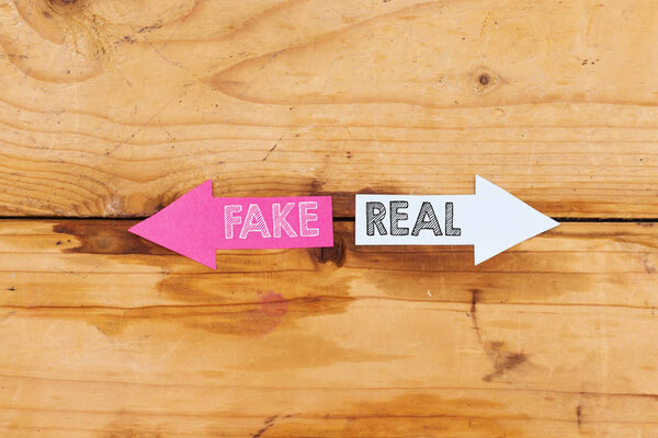Fake or Real Concept. Fake or Real written in paper arrows on wooden background. Business concept