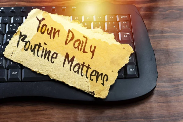 your daily routine matters concept on old carton tear card above black keyboard