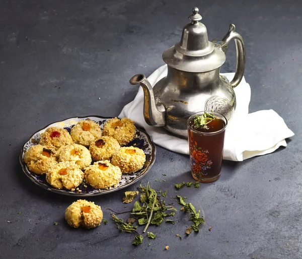 Traditional Moroccan Tea with Oriental Algerian sweet cookies( mchawak  named in arabic ), teacup and pot and mint leaves