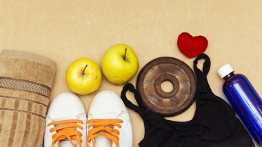Spor ekipmanları düz yatıyordu ve spor ayakkabıları, eski metal halter ve elma, su şişesi ve kalp yastık. Kavram sağlıklı yaşam tarzı, spor ve diyet.