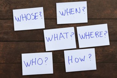 Sorular - Neden? Ne? Nerede? Tesis? Neden? Nasıl? ahşap arka plan üzerinde mavi çıkartmalar üzerinde. İş, metin, iletişim, bilgi, mesaj, not, kağıt, kelime