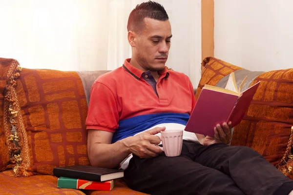 muslim man sitting on sofa moroccan  and reading a book, drinking arabic coffee