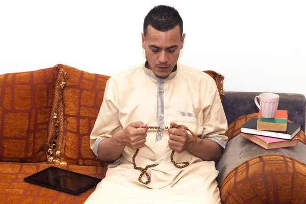 muslim man using misbaha to keep track of counting in tasbih and drinking coffee, reading books