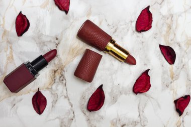 kırmızı ruj ve kurumuş gül yaprakları mermer arka planda