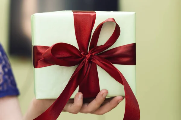 Hand Holding Gift In Package With red Ribbon, holidays concept