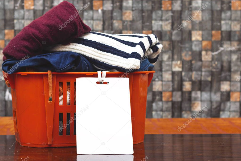 clothes in orange basket or box with blank card, donation concept