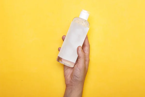 Makyaj cilt bakımını kaldırır. Yakından bir kadın, elinde bir şişe tutuyor. Kadın yüzünü losyonla temizliyor. Cilt bakım ürünüyle şişeyi tutan kadın..