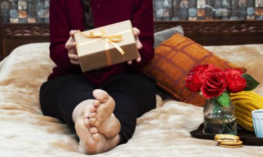 yatakta oturmuş ve bir kahve, gül vazo, çikolata kurabiye hediye kutusu, tatil kavramı (Noel, Şükran günü, doğum günü...) ve sabah sırasında tepsi içinde tutan kadın