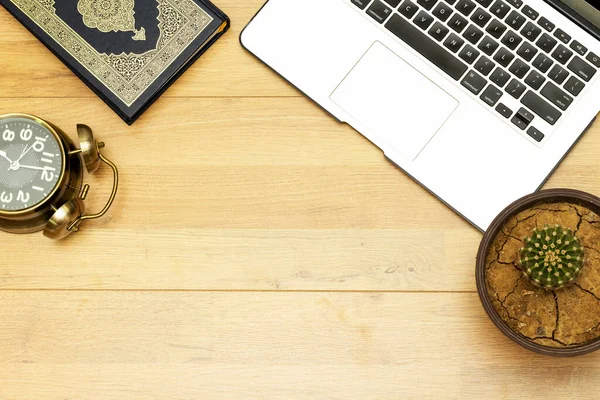 Modern Laptop 'ın ön görüntüsü, eldiven kaktüsü saksı bitkisi ve Kuran-ı Kerim' in Arapça kaligrafisi olan Kuran-ı Kerim saat 7 'yi gösteriyor.