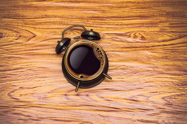 Çalar saat ve kahve konsepti ahşap masada.