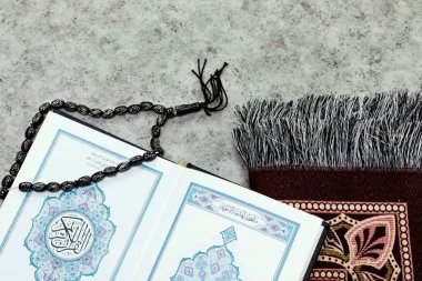 Kuran 'ın Arapça anlamı olan kutsal Kur' an ve siyah tespih ve namaz örtüsü.