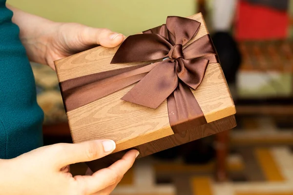 Hand Holding Gift In Package With brown Ribbon, holidays concept