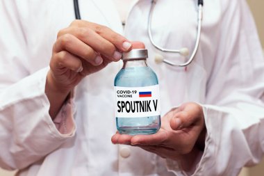 Coronavirus, Covid 19 virüsü, Spoutnik V yeni Rusya aşısı şişesi elinde mavi eldivenli sağlık tedavisi konsepti
