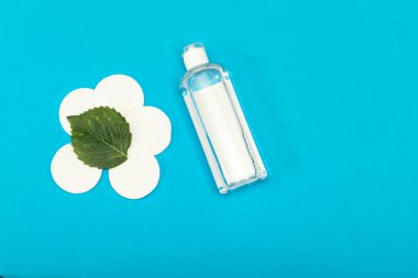 Makyaj cilt bakımını kaldırır. Plastik bir şişede yüz veya makyaj malzemesi çıkarıcı, pamuk pedler ve mavi arka planda ahşap pamuk tomurcuklar. Hijyen malzemeleri, güzellik aletleri ve deri.