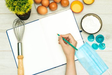 Boş tarif kitabını ve el ele tutuşmayı aç. Kalem, yumurta, un ve tıbbi maske. 