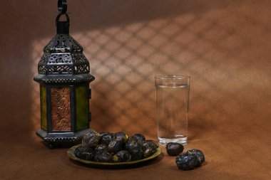 Ramazan iftar kavramı, Ajwa cam su ve fenerle meyveler ve bükülmüş pencere gölgesi olan bir kadın.