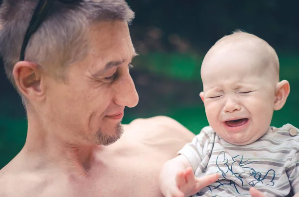 A happy father with crying child outdoors