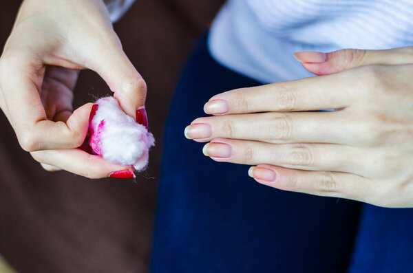 Woman with long red nails removing nail polish