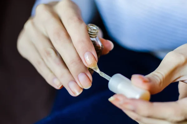Woman with long fingers and nails applying transparent nail base — ストック写真