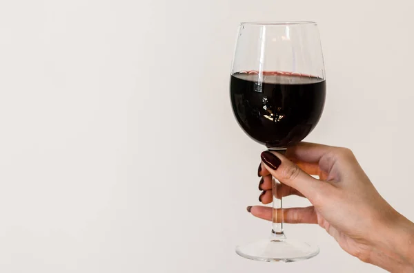 Segurando um copo de vinho com vinho tinto por mulher com dedos longos e unhas — Fotografia de Stock