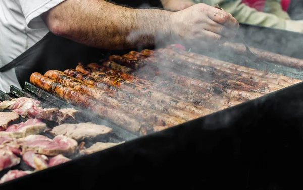 Argentina barbecue asado chorizo sausages and meat cooking on parilla grill