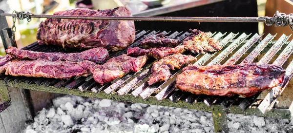 Argentina barbecue asado chorizo sausages and meat cooking on parilla grill