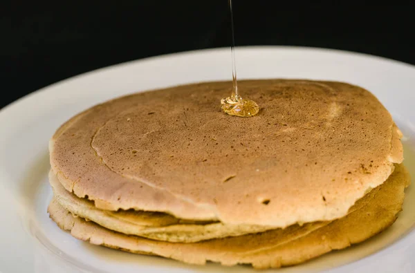 Close up of a bunch of tasty american pancakes and maple syrup poured over them — Stock Photo, Image