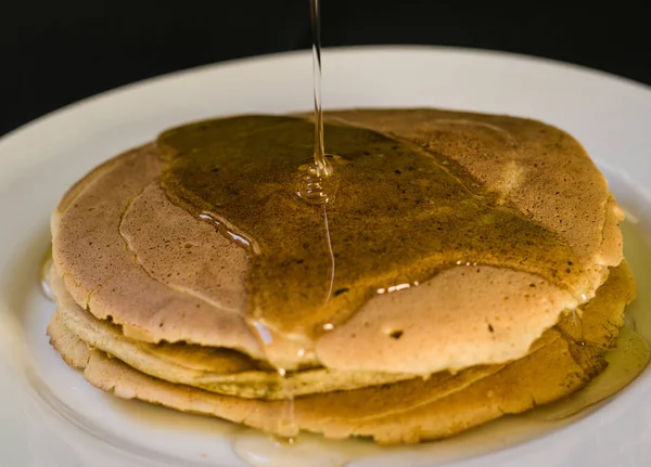 Close up of a bunch of tasty american pancakes and maple syrup poured over them — Stock Photo, Image