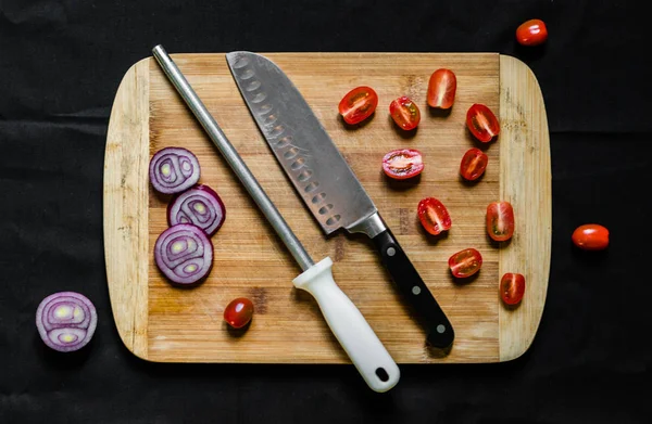 A knife sharpener and a chef knife on a cutting board with vegetables
