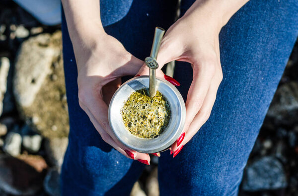 Young woman drinking traditional Argentinian yerba mate tea from calabash gourd