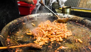 Şef bir sokak gıda pazarında domates sosu ve et ile makarna pişirme