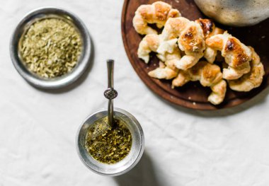 Yerba mate çayı, tahtadan yapılmış kruvasanlar ve beyaz arka planda çaydanlık.