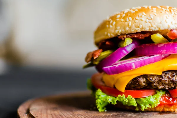 Hamburguesa sobre una mesa de madera sobre fondo negro — Foto de Stock