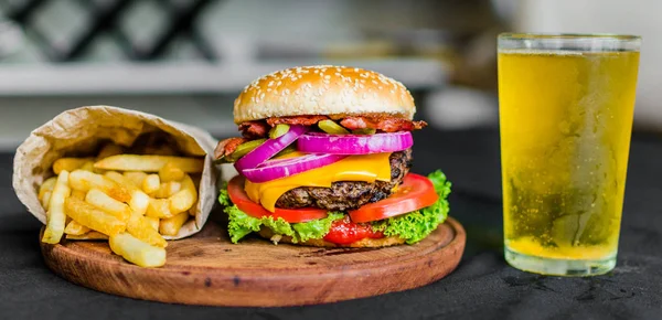 Burger i frytki na drewnianym stole na czarnym tle — Zdjęcie stockowe