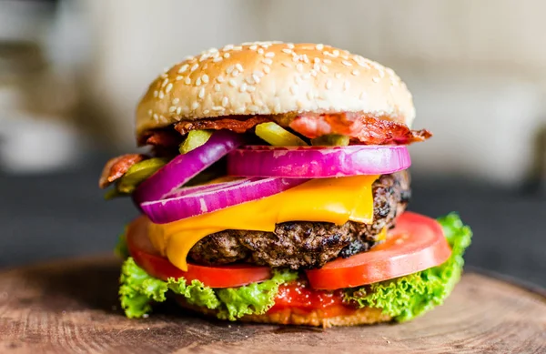 Hamburguesa sobre una mesa de madera sobre fondo negro — Foto de Stock