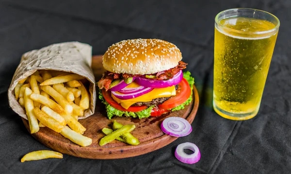 Burger i frytki na drewnianym stole na czarnym tle — Zdjęcie stockowe