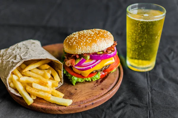 Hamburguesa y papas fritas sobre una mesa de madera sobre fondo negro — Foto de Stock