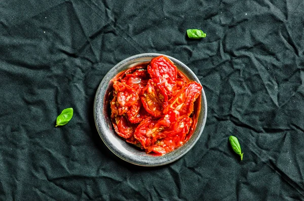 Тарілка з сушеними помідорами на чорному тлі — стокове фото
