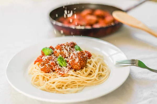 Паста-спагетти с фрикадельками в томатном соусе, сыр, падающий поверх него — стоковое фото
