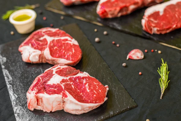 Wołowina wołowa steki z przyprawami i ziołami na czarnym tle — Zdjęcie stockowe
