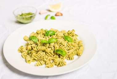 Beyaz arka plan karşı fesleğen ve peynir pesto ile Makarna