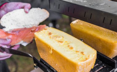 Somon ve raclette eritilmiş peynir ile sokak gıda pazarında sandviç hazırlanması