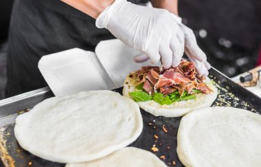 Sokak gıda pazarında arugula, parma ve peynir ile tortilla hazırlayan şef
